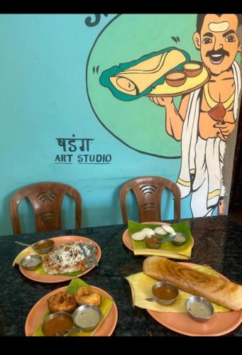 a table with plates of food on top of it at Mahesh Guest House in Hampi