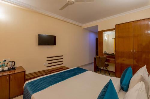 a bedroom with a bed and a tv on the wall at Blue Bliss Hotels By PPH Living Infantry Road in Bengaluru