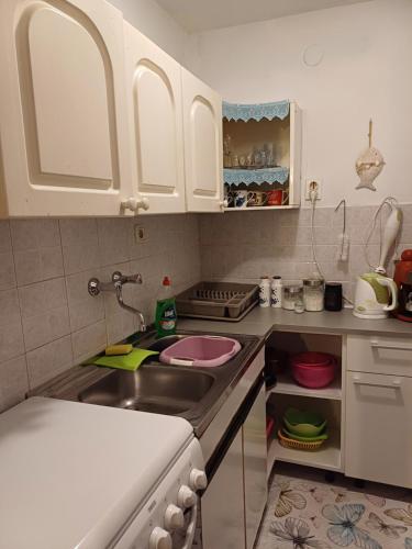 a kitchen with white cabinets and a sink at Apartment in green and quite area, close to beach in Šilo