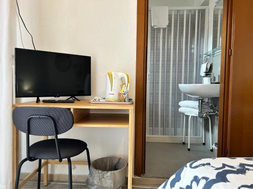 a bedroom with a desk with a television and a bed at Hotel Cecile in Pisa