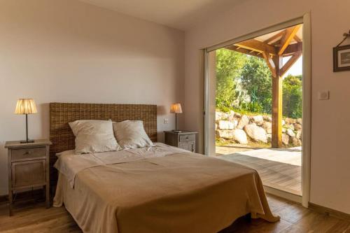 une chambre avec un lit et une porte coulissante en verre dans l'établissement Maison vue Mer et Maquis, à Olmeto