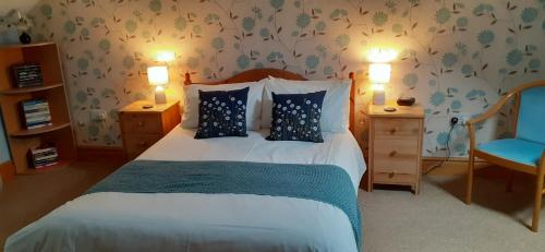 a bedroom with a bed with two lamps and a blue chair at Henblas Holiday Cottages in Abergele
