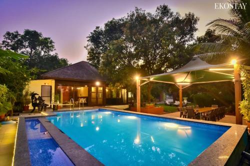 a swimming pool in front of a house at night at EKO STAY- BALI VILLA in Alibaug
