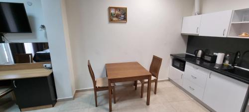 a small kitchen with a wooden table and chairs at Бутикови Студиа БРИТА in Kranevo