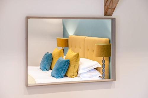 a mirror reflecting a bed with blue and yellow pillows at Dragonfly in Forcett