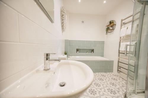 a white bathroom with a sink and a tub at Kingfisher in Forcett