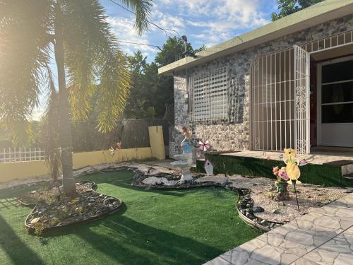um jardim com uma palmeira em frente a uma casa em Casa espaciosa con Jacuzzi, área sur PR em Juana Diaz