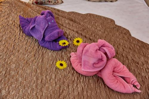 a pair of towels and flowers on a bed at Elite Mamaia Nord in Năvodari