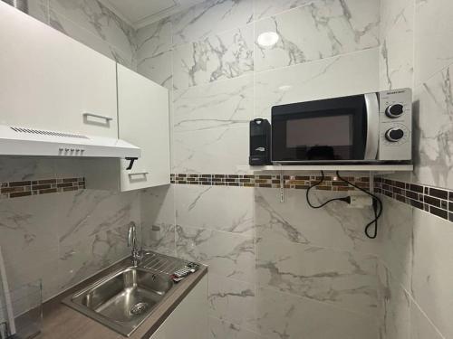 a microwave on a wall above a sink in a kitchen at studio avec terrasse en face la gare d’Enghien a 15 minute de paris gare du nord et a 10 mn de stade de France in Enghien-les-Bains