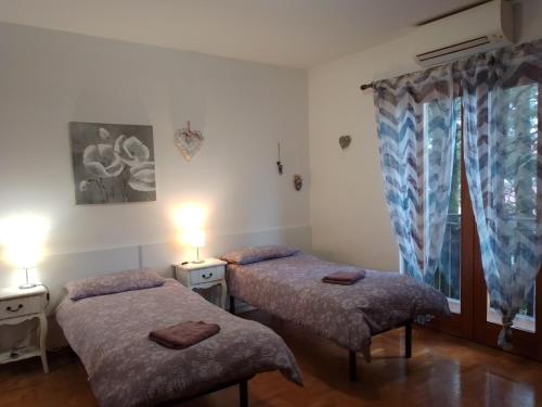 two twin beds in a room with a window at Cjase Paola in Cassacco