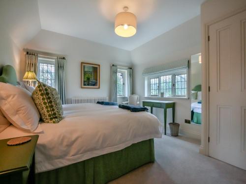 a bedroom with a large bed and windows at Keeds Cottage in Pulborough