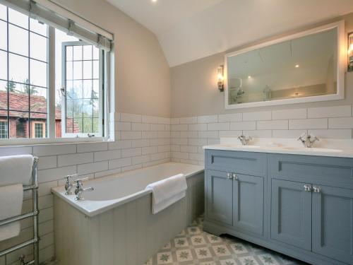 y baño con bañera, lavabo y espejo. en Keeds Cottage, en Pulborough