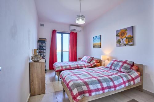 1 dormitorio con 2 camas y ventana en Seafront Townhouse in Birzebbuga, en Birżebbuġa