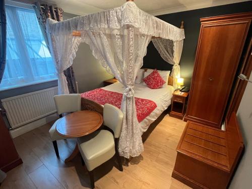 a bedroom with a canopy bed and a table and chairs at Sorrento Hotel & Restaurant in Cambridge