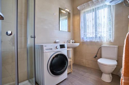 a bathroom with a washing machine and a toilet at Seafront Townhouse in Birzebbuga in Birżebbuġa