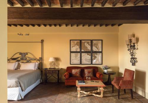 a bedroom with a bed and a chair and a table at Castello di Casole, A Belmond Hotel, Tuscany in Casole dʼElsa