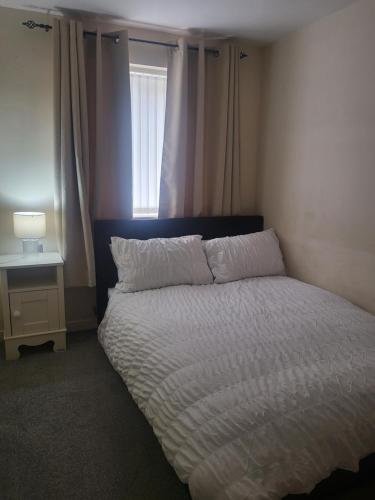 a bedroom with a bed with a white comforter and a window at Inviting 3-Bed House in Bolton in Bolton