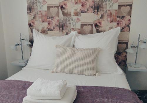 ein Bett mit weißen Kissen und eine Wand mit Herzen in der Unterkunft L'Amiral in Vichy