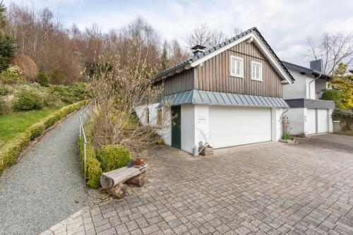a house with a white garage and a driveway at Haus Waldesruh in Bruchhausen