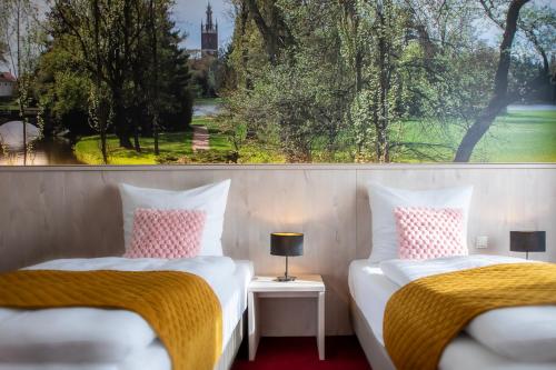 2 camas en una habitación con ventana grande en Hotel Restaurant Elbebrücke en Oranienbaum-Wörlitz