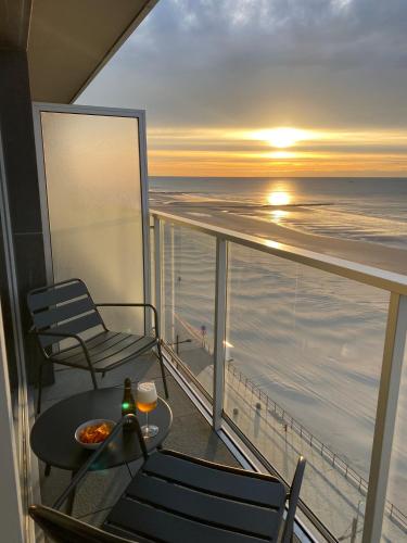 a balcony with a table and chairs and a sunset at Romanza Zeezicht in Middelkerke