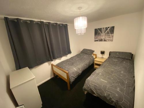 a bedroom with two beds and a chandelier at 2 Bedroom Modern Apartment in Earl Shilton