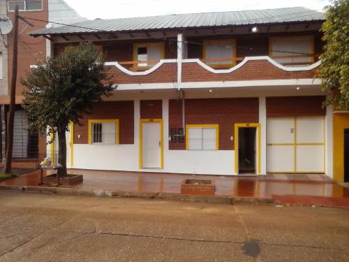 a red brick building with yellow doors on a street at Departamentos por dia EL TREBOL in Paso de los Libres