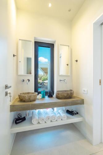 a bathroom with two sinks and two mirrors at Villa Euphoria in Pogoniá
