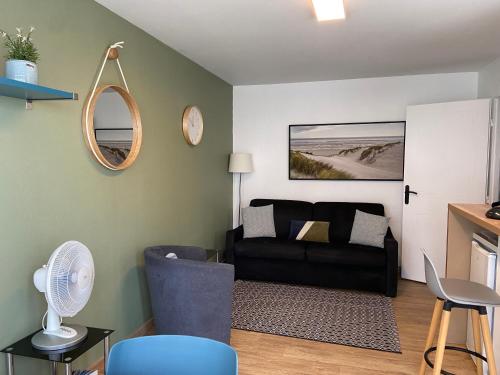 ein Wohnzimmer mit einem Sofa und einem Spiegel in der Unterkunft LE BON ENDROIT en bord de mer, vue mer , parking et wifi in Wimereux