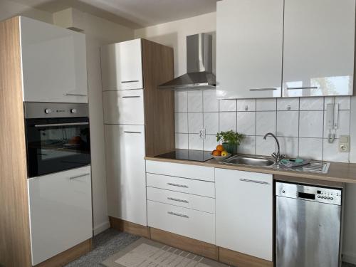 eine Küche mit weißen Schränken und einem Waschbecken in der Unterkunft Apartment Blaumuschel - LUB113 by Interhome in Lubmin