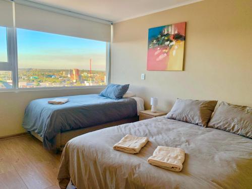 - une chambre avec 2 lits et une grande fenêtre dans l'établissement Departamento Centro Chillan - Parking -Vista - Factura, à Chillán