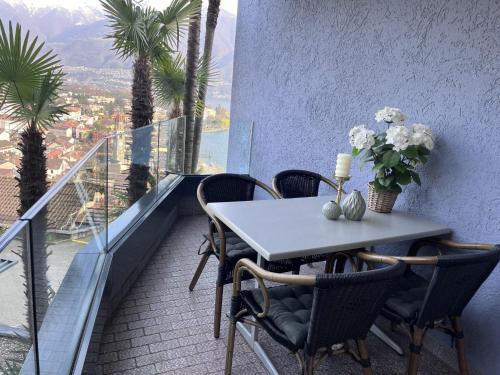 einen Tisch und Stühle auf einem Balkon mit Palmen in der Unterkunft Apartment Suite Classic-16 by Interhome in Ascona