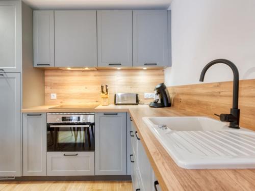 a kitchen with white cabinets and a sink at Apartment Village Cheval Spa Résidences-1 by Interhome in Lacanau-Océan