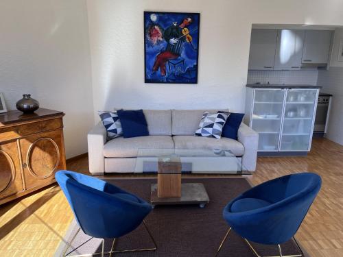 ein Wohnzimmer mit einem Sofa und zwei blauen Stühlen in der Unterkunft Apartment Suite Classic-12 by Interhome in Ascona