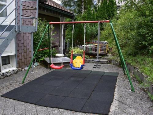 a swing set in a yard next to a house at Apartment Barmettlenstrasse 26 by Interhome in Engelberg