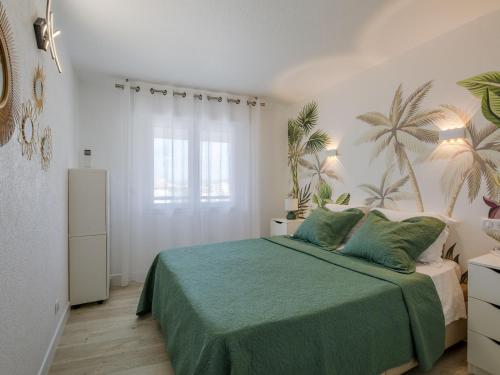 1 dormitorio con 1 cama con sábanas verdes y palmeras en la pared en Apartment Royal Marine-2 by Interhome en Fréjus