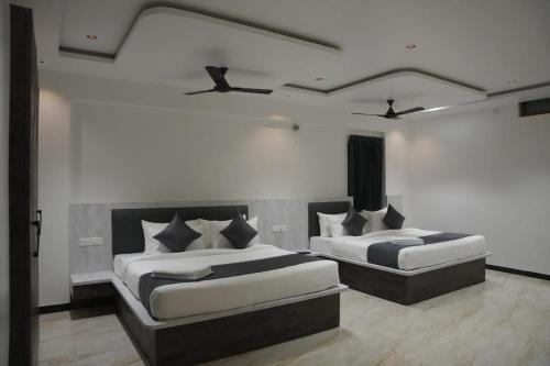 two beds in a room with two at Goldeye's Inn in Erode