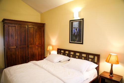 a bedroom with a white bed with a wooden cabinet at Majorda Beach Holiday Apartment in Majorda