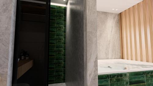 a bathroom with a bath tub and a green brick wall at Elite luxury suites Bali Rethymno in Bali