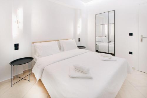 a white bedroom with a large white bed and a mirror at White&Wood in Patra