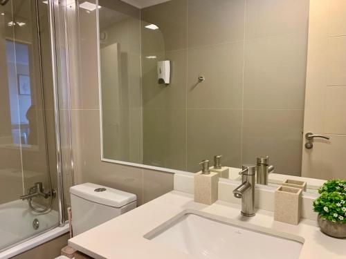 a bathroom with a sink and a toilet and a mirror at Departamento Centro Chillan - Parking -Vista in Chillán