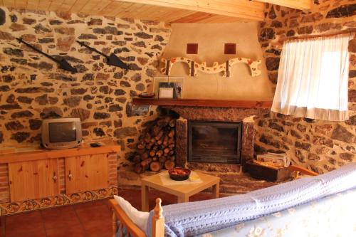 sala de estar con pared de piedra y chimenea en El Urogallo de Rucayo en Boñar
