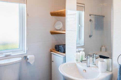 ein Bad mit einem Waschbecken, einem WC und einem Fenster in der Unterkunft Luxurious 2-Bed Lodge in St Helens Ryde in Saint Helens
