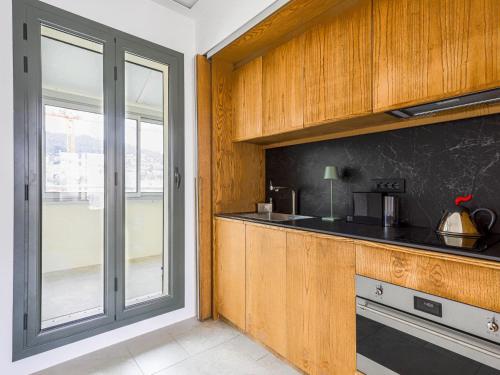 une cuisine avec des armoires en bois et une fenêtre dans l'établissement Apartment Le Copacabana by Interhome, à Nice