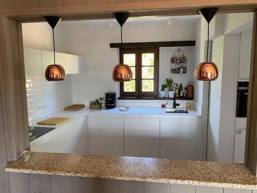 a kitchen with white cabinets and a window and two lights at Maison Conviviale, Vue Mer in Propriano