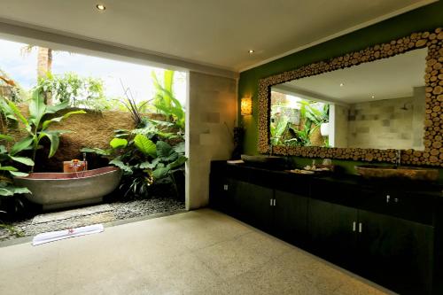 a bathroom with a tub and a large mirror at Ubud Virgin Villa in Ubud