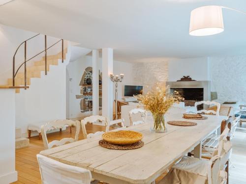 a white dining room with a wooden table and chairs at Villa Scarlette by Interhome in Saint-Briac-sur-Mer