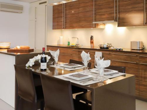 a kitchen with a table with wine bottles and chairs at Apartment Les Terrasses C1-7 by Interhome in Montreux