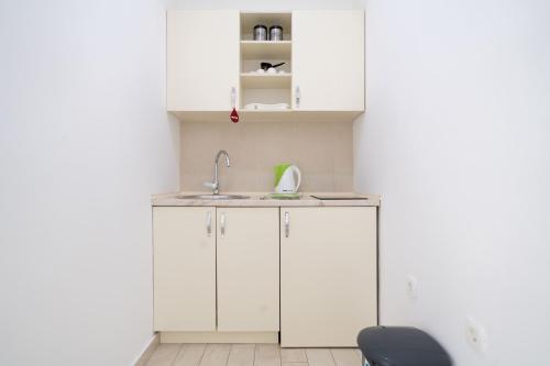 uma cozinha com armários brancos e um lavatório em Mariner Apartments em Sutomore