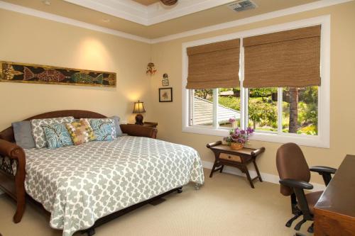 a bedroom with a bed and a desk and two windows at Wai'ula'ula D201 in Hapuna Beach